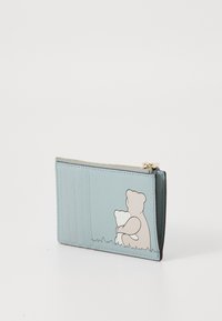 Light blue wallet with bear illustration. Smooth leather, zip closure, ridged texture on one side, gold-tone hardware. Compact rectangular shape.
