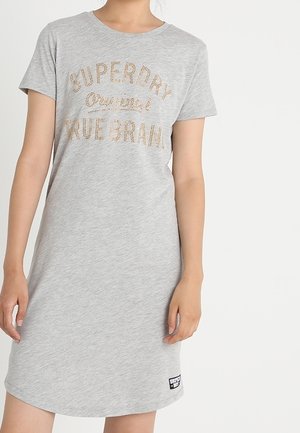 Grå klänning med kort ärm som har "SUPERDRY Original True Brand" tryckt i glänsande guld. Mjuk tyg, rund halsringning och en etikett i nederkant.