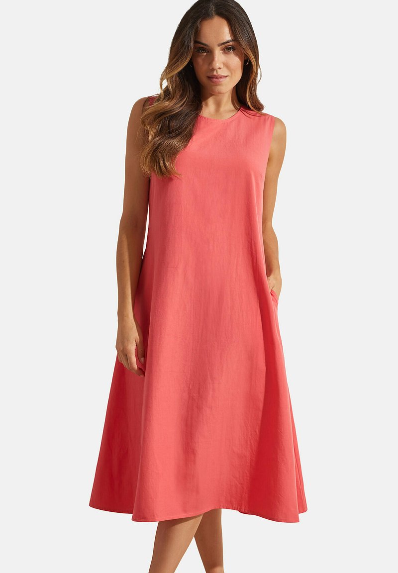 Robe sans manches corail en tissu doux, de forme A-line, longueur genou, avec des poches latérales et une finition lisse et sans embellissements.