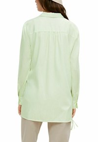 Camicia verde chiaro con colletto, a strisce verticali, dalla vestibilità comoda, maniche lunghe e dettagli annodati ai polsini, realizzata in un tessuto morbido e leggero.