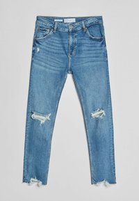 Jeans de mezclilla de color azul claro con desgastes y roturas en las rodillas y bordes deshilachados. Diseño clásico de cinco bolsillos con cremallera y cierre de botón.