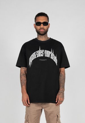 Sort bomulds T-shirt med korte ærmer, prydet med hvid grafisk tekst i en buet design. Sættes sammen med beige cargo bukser.