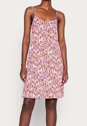 Frau trägt ein ärmelloses, knielanges Kleid mit rosa, roten und gelben Blumenmustern und dünnen doppelten Trägern.