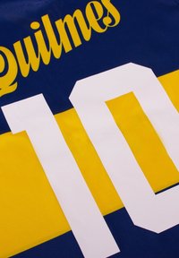 Blauw en gele sporttrui met de naam "Quilmes" in het geel boven het nummer "10" in grote witte letters op de achterkant.