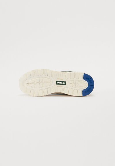 Sko såle med gummimateriale; for det meste hvit med teksturerte gripe mønstre; har en blå aksent og "POLO" logo i midten.
