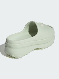 Clog verde moldado com uma sola elevada e texturizada. Design arredondado e parte traseira aberta, apresentando um logótipo subtil na superfície superior.