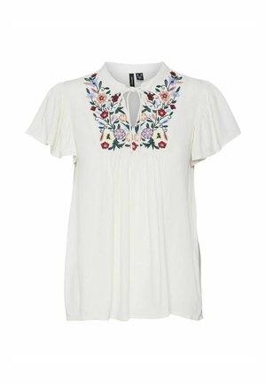 Balta blūze ar īsām, plūstošām piedurknēm, dekorēta ar krāsainiem ziedu izšuvumiem ap kaklu un ar saites detaļu. Viegls audums.
