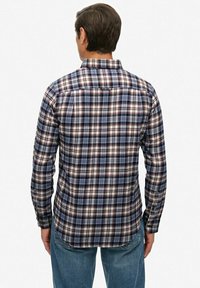 Blauwe, rode en witte geruite lange mouwen shirt met een kraag en knoopsluiting. Katoenen materiaal met een gladde textuur. Achteraanzicht.