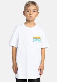 Vit bomull t-shirt med korta ärmar, med en färgglad "DC Shoe Company" logotyp på vänster bröst. Enkel design, avslappnad passform.