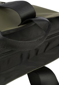 Groene synthetische tas met zwarte stofafwerking en ritsen. Het interieur heeft een zachte stoffen voering en een gestructureerd ontwerp.