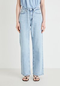 Ανοιχτό μπλε ψηλόμεσες φαρδιές τζιν, φτιαγμένες από τζιν ύφασμα, με κλείσιμο από κουμπί και ξεχωριστή ζώνη που δένει στη μέση.