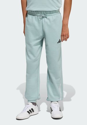 Pantalon de survêtement turquoise clair avec une taille élastique, des poignets fuselés et des accents de logo Adidas noirs. Texture douce, coupe décontractée et droite.
