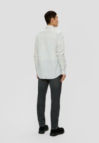 Weißes gemustertes Hemd mit Button-Down-Kragen, langen Ärmeln und geradem Saum, kombiniert mit dunkelgrauen Jeans und schwarzen Schuhen. Rückansicht.