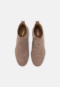 Brązowe botki zamszowe z elastycznymi panelami po bokach i pętlami do ściągania na pięcie. Płaskie gumowe podeszwy i gładkie wykończenie wewnętrzne.