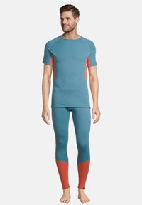 Completo sportivo color teal composto da una maglietta a maniche corte con dettagli arancioni e leggings attillati in una combinazione di colori simile con pannelli a contrasto.
