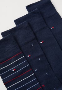 Ensemble de chaussettes navy comprenant des modèles unis et rayés. Les rayures incluent des accents blancs et rouges ; une paire présente des détails de logo dans des couleurs contrastées.