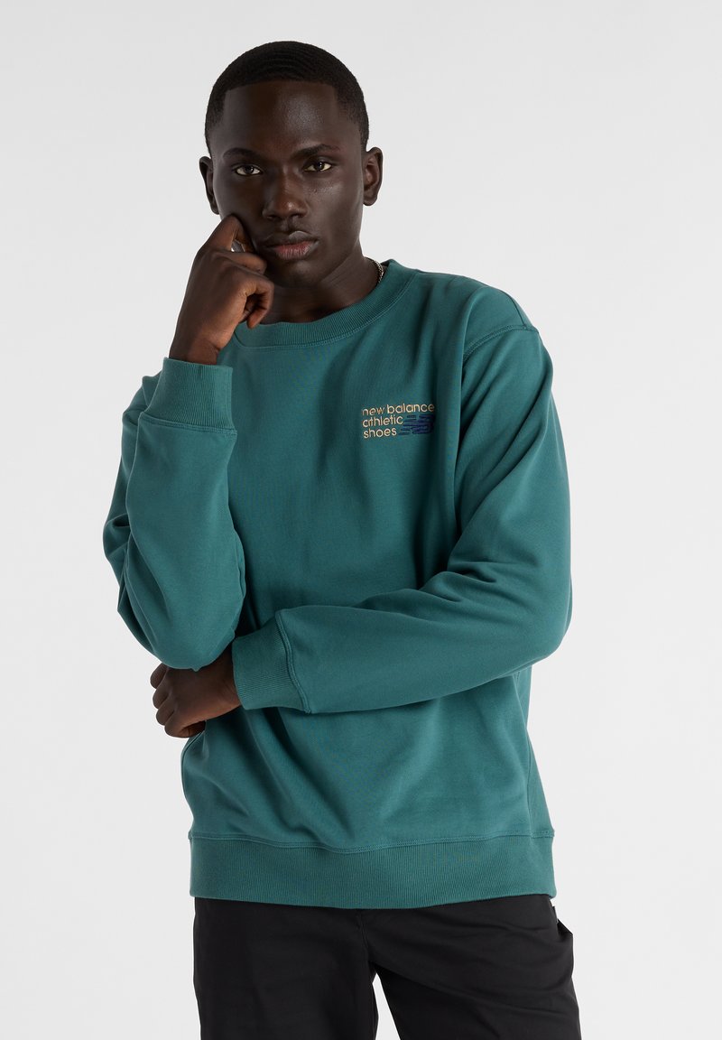 Sudadera azul verdosa con puños y dobladillo acanalados. Presenta "new balance athletic shoes" bordado en colores contrastantes en el pecho.