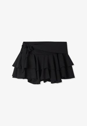 Gonna nera arricciata con balze a strati, dotata di una larga fascia in vita e di un dettaglio con fiocco sul davanti. Realizzata in tessuto leggero.