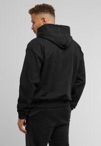Black hooded sweatshirt made of soft fabric, featuring a relaxed fit, ribbed cuffs, and hem. Minimalistic design with no visible logos.