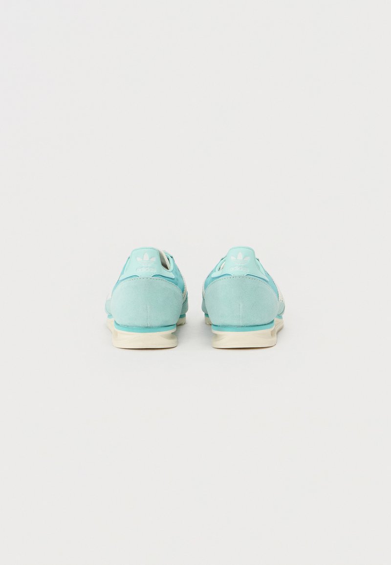 Zapatillas de ante azul claro con un upper texturizado, que cuentan con una suela y un talón blancos, y un detalle del logo en la parte trasera en un color contrastante.
