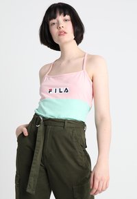 FILA fargeblokket tanktopp i rosa og mintgrønn, med en logo foran, kombinert med høyt liv olivenfargede cargo bukser med lommer.