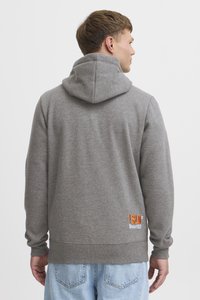 Szara bluza z kapturem o miękkiej fakturze z pomarańczowym haftowanym logo "ISLD Since 1993" na dolnym prawym boku.