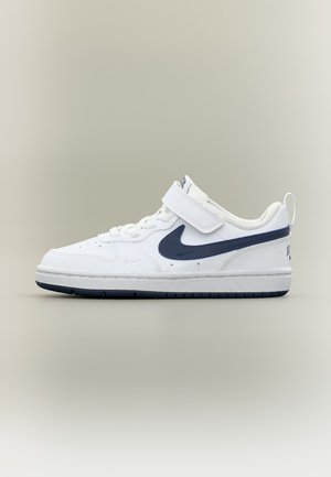 Λευκό sneaker χαμηλού ύψους με σκούρο μπλε λογότυπο Nike, ιμάντα βέλκρο, κορδόνια και θηλιά στη φτέρνα σε απλό φόντο.