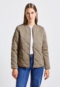 Přikrývková bomber bunda v béžové barvě, s kulatým výstřihem, zipem vpředu a patentními knoflíky. Materiál má hladkou texturu s diamantovými vzory.