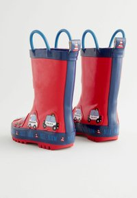 Les bottes de pluie en caoutchouc rouge et bleu sont décorées de motifs de policiers et d'ambulances en dessin animé, possèdent des semelles texturées et des poignées bleues ornées d'accents en forme de cônes de signalisation.