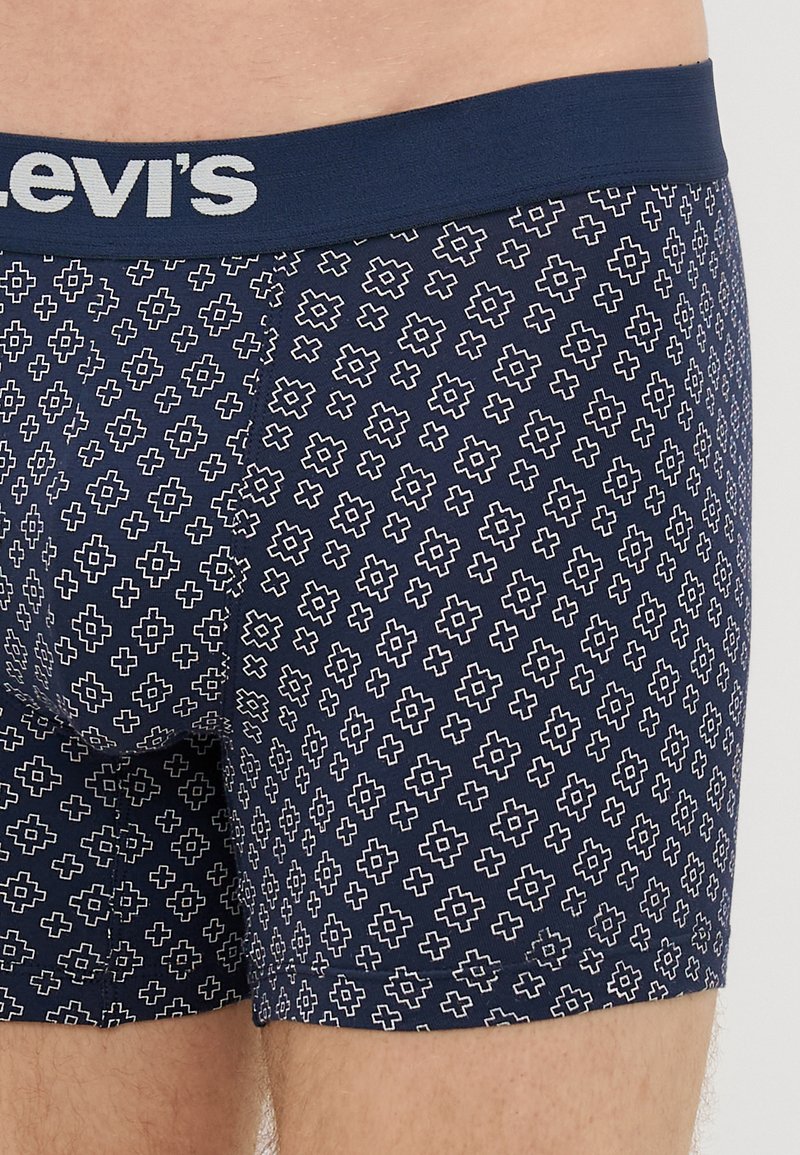 Navy blue boxer shorts with a geometric white pattern. Features a branded elastic waistband with "Levi's" in gray lettering. Smooth texture.