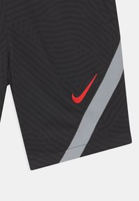 Mustat urheilushortsit, joissa on aaltoileva tekstuuri, harmaa sivupaneeli ja punainen Nike-logo. Valmistettu kevyestä materiaalista.