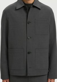 Pelēks žakets, kas izgatavots no teksturēta auduma, ar apkakli, četriem priekšējiem kabatām un pogu aizdari. Minimalistisks dizains ar taisno piegriezumu.