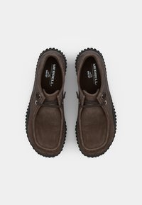 Scarpe in suede marrone con forma arrotondata, caratterizzate da una tomaia testurizzata, una suola in gomma nera contrastante e accenti in pizzo grigio.