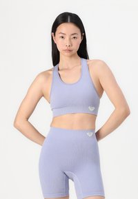 Lavender ribbed sports bra and high-waisted shorts with heart logo accents. Material offers stretch and comfort for activewear.
