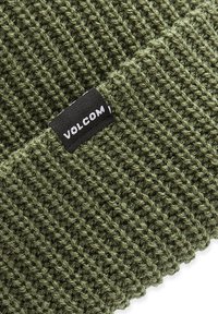 Grøn strikket beanie med et struktureret mønster, udstyret med et sort mærke med "VOLCOM" i hvid. Materialet ser blødt og strækbart ud.