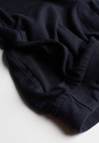 Donker marineblauw katoenen stof met een zachte textuur, voorzien van een elastische tailleband en plooien, losjes verzameld voor comfort.