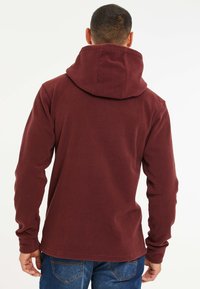 Weinrote Fleece-Hoodie mit einer Kordelzugkapuze und langen Ärmeln, ausgestattet mit einer glatten Textur und einem lockeren Schnitt. Die Rückansicht zeigt keine zusätzlichen Details.