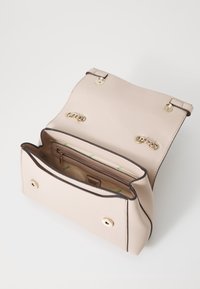 Cremefarvet syntetisk håndtaske med guld hardware, to magnetiske lukninger og en struktureret overflade. Indvendig har den en lynlåslomme og brandlogo.