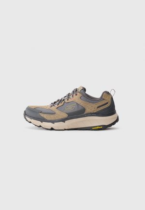 Beige and gray sneaker with mesh and suede upper, thick white sole, rounded toe, and Goodyear logo on the front.