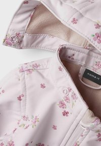 Rosa blommig, vadderad jacka med en mjuk fleeceinteriör. Har tryckknappar och dragkedja, samt små lavendelfärgade och gröna blommönster.