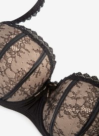 Czarny koronkowy stanik z kwiatowym wzorem, przezroczystymi miseczkami i czarnymi wykończeniami. Posiada regulowane ramiączka oraz wsparcie w postaci fiszbin. Teksturowany materiał, misternie zdobiona koronka.