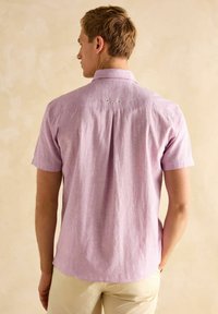 Lühikese varrukaga särgid heledast roosast kangast, millel on tekstuur, punktikrae ja kaks väikest silmust taga.