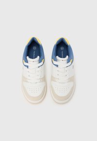 Pantofi sport albi și bej cu guler căptușit albastru și galben, șireturi albe, vârf perforat și logo Tommy Hilfiger pe limbă.