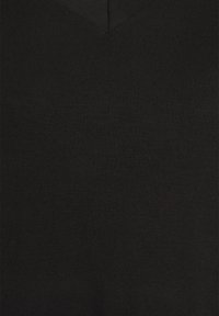 Nära bild av svart ribbad tyg med en V-halsform, som visar struktur och sömnadsdetaljer.