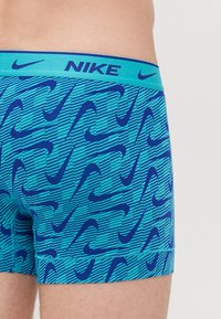Nike blå kalsonger med ett mönster av mörkblå swooshes och horisontella ränder, med en matchande elastisk midja.