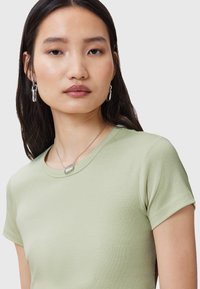 T-shirt fitted verde chiaro con maniche corte, realizzato in tessuto liscio. I dettagli salienti includono un colletto rotondo e una leggera texture.