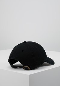 Gorra de béisbol negra con visera curva, hecha de tela de algodón. Cuenta con una correa ajustable con un cierre de metal en la parte trasera.