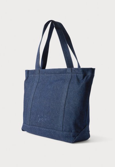 Τσάντα tote από τζιν σε σκούρο μπλε με δύο μακριές λαβές, διαθέτει δομημένο σχήμα, ραμμένες ραφές και διακριτικό λογότυπο στο μπροστινό μέρος.