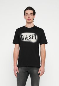 Μαύρο βαμβακερό T-shirt με ανάγλυφο, αντίθετο γραφικό της λέξης "DIESEL" στο μπροστινό μέρος. Κοντά μανίκια και στρογγυλή λαιμόκοψη.