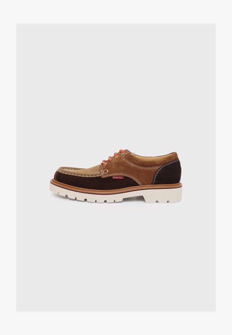 Chaussure derby homme en daim marron avec panneaux beige et marron foncé, œillets orange, semelle blanche et coutures visibles sur fond blanc.